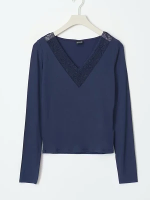 Mörkblå topp med spetsdetalj - Mörkblå långärmad topp med v-ringning och dekorativ spets längs ringningen. Tunn och mjuk kvalitet, perfekt för en stilren look. Enkel att matcha med olika outfits.