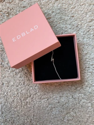Silverarmband med blixt från Edblad - Snyggt och stilrent armband i silver från Edblad med en blixtformad detalj på en tunn kedja. Kommer i original rosa ask. Perfekt för dig som gillar minimalistiska smycken med en cool twist.