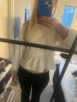 Vit blus med resår i midjan - Säljer en vit blus med långärmad design och resår i midjan som ger en snygg form. Blusen har en lätt struktur i tyget och rund halsringning. Perfekt att styla med både jeans och kjol för en fräsch look.