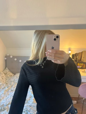 Svart  tröja med vida ärmar - Svart relativt stretchig tröja, ganska ”lös” vid halsen och inte jätte tight om kroppen. Ingen aning vad materialet heter så skriv för fler tydliga bilder. Använd max 5 gånger men fortfarande mycket bra skick. Lite volangaktig längst ner på tröjan (syns inte på bilden då jag vikt upp den lite) och vida ärmar. 