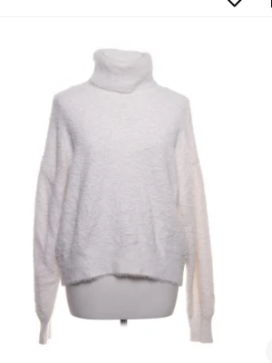  polotröja - Mysig vit stickad polotröja med fluffig textur och avslappnad passform. Tröjan har långa ärmar och hög polokrage, perfekt för kalla dagar. Materialet ser ut att vara en mjuk syntetblandning som ger en skön känsla.