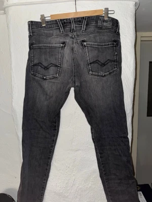 Grå slim fit jeans med slitningar// Replay - Säljer ett par grå slim fit jeans från Replay med coola slitningar och tvättad look. Jeansen har två bakfickor med dekorativa sömmar och bälteshällor. Materialet är mjukt denim som ger en skön passform och trendig stil. Längd 34