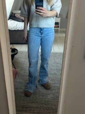 Ljusblå bootcut jeans - Säljer ett par ljusblå raka jeans med hög midja och klassisk femficksdesign. Jeansen har en avslappnad passform och är tillverkade i denim med snygg tvätt. Perfekt avslappnade. Med slits.