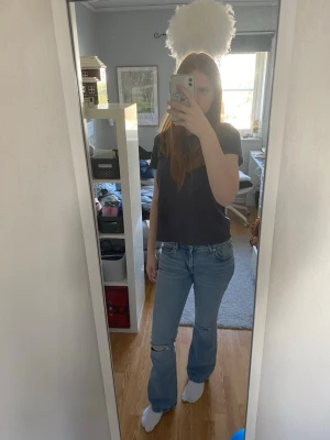 Ljusblå bootcut jeans med slitning - Säljer ett par ljusblå bootcut jeans med slitning vid knät. Jeansen är från Lager 157 och är låg midjade. Perfekta för en avslappnad och trendig look. Materialet är denim i bomull. Passar dig som gillar en lite vidare passform nedtill.