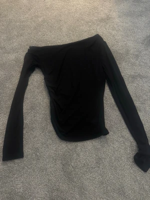 Svart oneshoulder topp med lång ärm - Tajt långärmad tröja från shein, den ger en fin figur då den är lite insydd på ena sidan av midjan och går att ha som one shoulder. Storlek xs. Oanvänd.