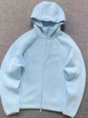 Ljusblå Nike x Nocta hoodie med dragkedja - Snygg ljusblå hoodie från Nike x Nocta med hel dragkedja och huva. Tillverkad i mjukt material som känns skönt mot huden. Minimalistisk design med liten vit Nike-logga på bröstet och diskreta sömmar för en clean look. Perfekt för dig som gillar sportig och stilren streetwear.