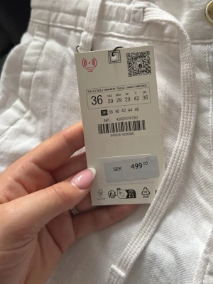 Vita linnebyxor med dragsko - Säljer ett par vita linnebyxor i storlek 36. Byxorna har dragsko i midjan och raka ben för en avslappnad look. Perfekta för varma dagar och lätta att matcha med olika toppar. Materialet är luftigt linne som ger en skön känsla.