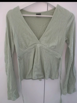 Ljusgrön omlottopp med långa ärmar - Snygg ljusgrön omlottopp med v-ringning och långa ärmar. .