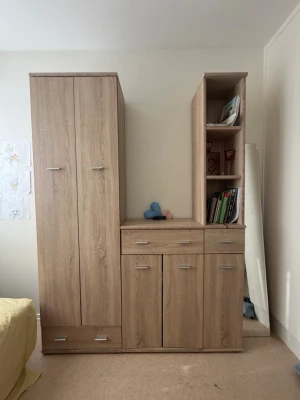 Bokhylla  - Snygg garderob i ljusbrunt trä med flera skåp, lådor och öppna hyllor. Perfekt för förvaring av kläder, böcker eller dekorationer. Modern design med silverfärgade handtag och slät yta. Passar bra i sovrum eller vardagsrum.