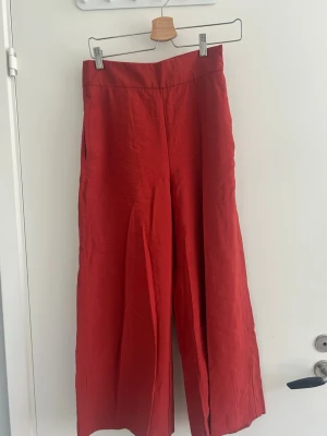 Röda byxor från lindex  - Snygga röda byxor från Lindex i storlek 36. Byxorna har hög midja, vida ben och sidfickor. Tillverkade i ett luftigt material som passar perfekt till sommaren.  Enkel design utan synliga knappar eller dragkedja.