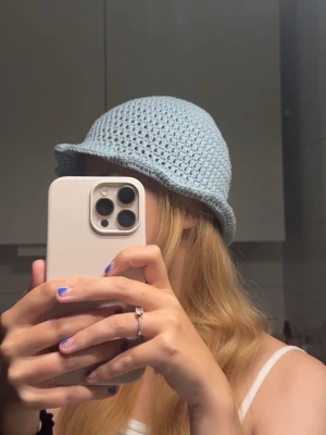 Ljusblå virkad bucket hat - Säljer en ljusblå egenvirkad bucket hat i mjukt garn. Handtvätt rekommenderas utan sköljmedel eller ett mjukt program på tvättmaskin i tvättpåse