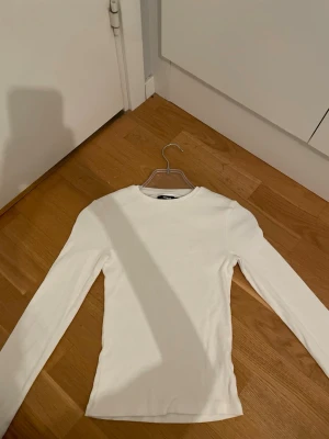 Vit ribbad långärmad topp BikBok - Säljer en vit långärmad topp från BikBok i storlek XS. Toppen är ribbad och har en enkel, tight passform med rund halsringning. Perfekt basplagg att styla till allt och superenkel att matcha med olika outfits.