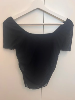 Svart mesh offshoulder topp - Snygg svart mesh topp från SHEIN  med offshoulder-design och korta ärmar. Tunn och genomskinlig med en tight passform som ger en trendig look. Perfekt att styla med höga jeans eller kjol för en cool vibe.