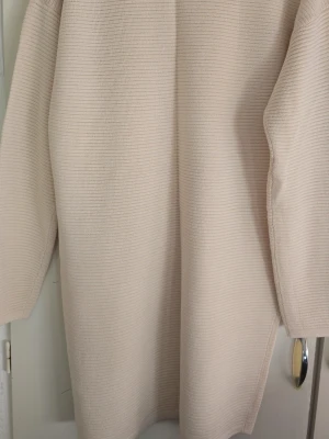 Beige oversized stickad tröja - En enkel och stilren beige stickad tröja i oversized modell. Tröjan har långa ärmar och rak passform, perfekt för lager på lager. Materialet känns mjukt och bekvämt, och färgen är lätt att matcha med olika outfits.