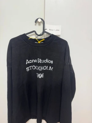 Acne Studios tröja - Cool svart långärmad topp från Acne Studios med vit text 'Acne Studios STOCKHOLM 1996' på bröstet. Klassisk rund halsringning och relaxed fit. Perfekt till jeans eller kjol för en avslappnad look. Storlek Medium etiket finns kvar. Säljs för 1200 men priset går att diskutera.