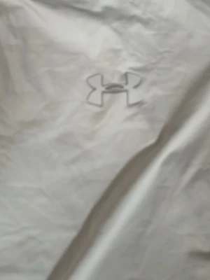 Ljusgrå tränings-tshirt Under Armour - Snygg ljusgrå tränings-tshirt från Under Armour med diskret logga på bröstet. Tillverkad i ett lätt och snabbtorkande funktionsmaterial som passar perfekt till gymmet eller löprundan. Klassisk rund hals och korta ärmar.