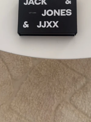 Presentkort Jack & Jones 500kr värde  - Säljer ett presentkort från Jack & Jones och JJXX. Kortet kommer i en svart ask med vit text och är perfekt om du vill ge bort något flexibelt till någon som gillar mode och streetwear. Swishbetalning 