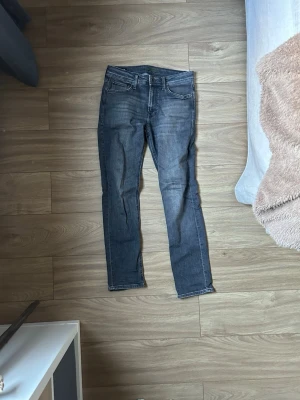 Mörkgrå slim fit jeans - Snygga mörkgrå slim fit jeans med raka ben. Jeansen är denim med kontrastsömmar för en modern look. Perfekta till en avslappnad stil och passar till det mesta i garderoben.