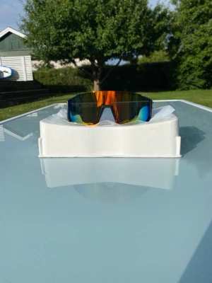 Sportsolglasögon - Hej! Säljer ett par riktigt ”snabba” och snygga sportsolglasögon med spegelglas i nyanserna orange/grön/blå. Såklart UV400: Blockerar 100% av skadliga strålar Design: Bekväm lättviktsram för långa pass. Modellen är i populära Sutro stilen  med stor lins och ramlös nederkant - utmärkt budgetalternativ som fyller exakt samma funktion, inte Bliz. Passar perfekt för ditt nästa äventyr oavsett om det är på en slingrig stig i Alperna eller på gatan utanför huset! Tveka inte att höra av dig vid frågor!