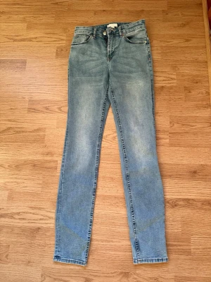Ljusblå skinny jeans med hög midja - Säljer ett par nya/oanvända ljusblå skinny jeans med hög midja och klassisk femficksdesign. Jeansen har en lätt tvättad look och raka benslut. Perfekta för en avslappnad och trendig stil. Materialet känns mjukt och stretchigt för extra komfort. Obs! Saknar prislapp/tags! 