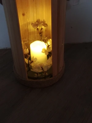 Träljuslykta med LED-ljus och blommor - Säljer en dekorativ ljuslykta i ljust trä med ett batteridrivet LED-ljus inuti. Lyktan är dekorerad med konstgjorda vita blommor och har en rund form med repdetalj längst ner. Perfekt som mysig inredningsdetalj.