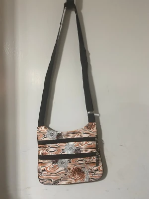 Dam axelväska - . Väskan har två dragkedjefack på framsidan och ett justerbart svart axelband. Perfekt för dig som gillar unika accessoarer och vill ha plats för det viktigaste. 89kr/st , helt ny 