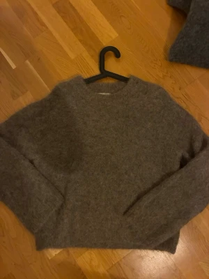 Brun fluffig alpacka  tröja Gina Tricot - Mysig brun stickad tröja från Gina Tricot i alpackablandning. Köpt för 999kr och knappt använd. Tröjan har en fluffig textur, rund halsringning och långa ärmar. Perfekt för kalla dagar och enkel att matcha med jeans eller kjol.