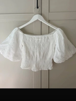 Vit offshoulder topp - Säljer en vit offshoulder tröja från H&M💕tröjan är stretchig med ballong ärmar och kan bäras både på och utanför axlarna 