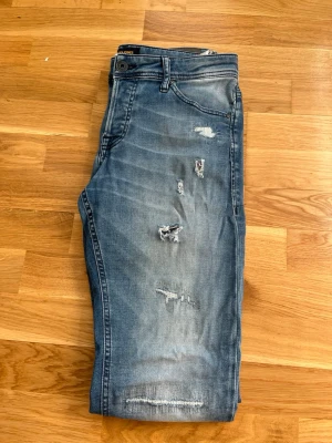 Blå slitna skinny jeans - Säljer ett par blå jeans med slim fit och slitningar på låren och knäna. Jeansen har klassisk femficksdesign, normal midja och dragkedjegylf. Det finns tecken på användning, lite extra på bakdelen men fortfarande mycket kvar o ge. Skickas snabbt och hör av er vid minsta funderingar!!