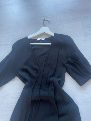 Svart Carin Wester Klänning - Snygg svart långklänning med knyt vid midjan. Använd en gång efter jag fick den i present. Inte för varm så perfekt till sommaren med!