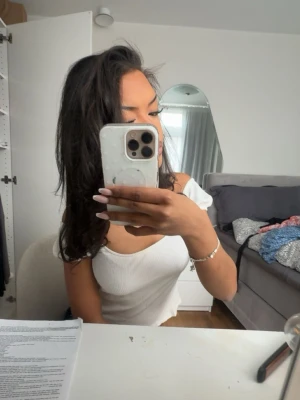 Vit ribbad croppad topp - Säljer en vit ribbad croppad topp med korta ärmar och lätt vågig kant nedtill. Toppen har en snygg, figurnära passform och är tillverkad i ett mjukt, stretchigt material. Perfekt till jeans eller kjol för en trendig look🌸