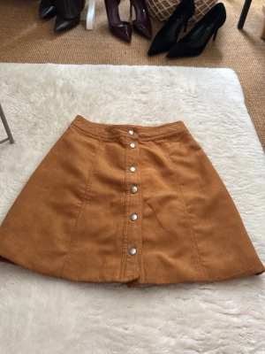 Brun manchesterkjol med knappar - Snygg brun kortkjol i manchester med silverfärgade knappar framtill. Från h&m (divided) storlek xs (34) 