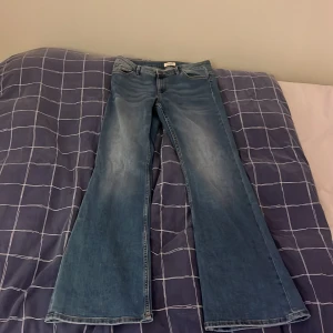 högmidjade Blå bootcut jeans med utsvängda ben - Säljer ett par klassiska blå bootcut jeans med utsvängda ben och femficksmodell. Jeansen har normalhög midja och är tillverkade i denim. Perfekta för dig som gillar retrostil och vill ha ett par riktigt snygga jeans med bred siluett.