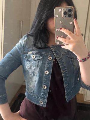 Jeans bolero - Snygg kort jeans bolero från Orsay i klassisk blå denim. Jackan har rundad krage, silverfärgade knappar och två bröstfickor med lock. Perfekt för att lyfta en outfit med en trendig touch🩵💋