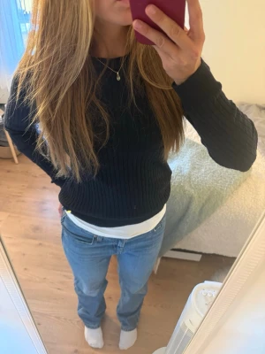 Mörkblå kabelstickad tröja - Snygg mörkblå kabelstickad tröja med rund halsringning och långa ärmar. Tröjan har en klassisk, figurnära passform och är tillverkad i ett mjukt stickat material. Perfekt att matcha med jeans för en enkel och stilren look.