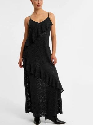 Svart långklänning med volang från Kappahl  - Svart långklänning från Kappahl med tunna axelband och v-ringad hals. Klänningen har dekorativa volanger som går diagonalt över framsidan och är tillverkad i ett spetsliknande material. Perfekt för dig som vill ha en elegant och trendig look.