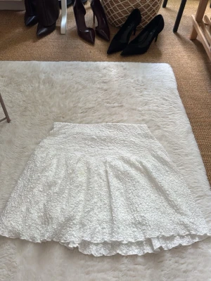 Vit volangkjol med struktur - Supersöt vit kortkjol med volangkant och strukturerat tyg. Från Gina tricot och i storlek S tyvärr är lappen med märke och storlek borta men den är ganska ny och använd sällan. 