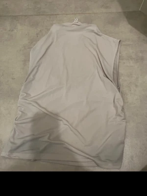 Beige ärmlös tröja  - Säljer en enkel och stilren beige kort tröja  med hög hals och ärmlös design. Tröjan  har en rak passform. Perfekt för dig som gillar minimalistisk stil. Storleken är L