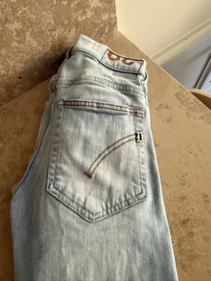Ljusblå Lee jeans med raka ben - Säljer ett par ljusblå jeans från dond up med raka ben och klassiska bakfickor. Jeansen har snygga kontrastsömmar i brunt och en liten metalllogga där det står ett stort D på fickan. Tillverkade i mjuk denim som ger en avslappnad vibe. Och sitter rätt tajt perfekt till sommaren vill ni ha fler bilder är det bara att fråga mvh MW