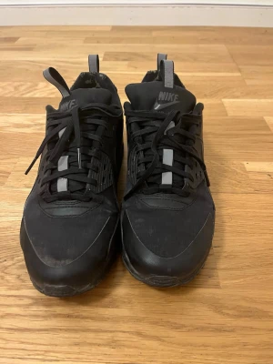 Svarta Nike Air Max sneakers - Säljer ett par helsvarta Nike Air Max sneakers med klassisk siluett och synlig luftdämpning i sulan. Skorna har svarta skosnören, diskreta grå detaljer och är tillverkade i en mix av textil och syntetmaterial. Perfekta för dig som gillar streetwear och sportig stil. Pris kan diskuteras. Skorn har reflex.