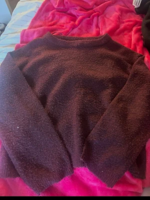 Vinröd stickad tröja - Mysig vinröd stickad tröja med enkel design och rund hals. Tröjan har lång ärm och är gjord i ett mjukt, fluffigt material som känns skönt mot huden. Perfekt för kyliga dagar när du vill vara både bekväm och snygg.