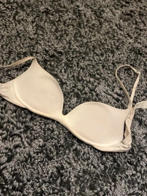 Intimissimi bh 75A - Stilren beige balconette-bh med tunna, justerbara axelband och slät yta. Bh:n har lätt vadderade kupor och ger ett lyft utan synliga sömmar. Perfekt under toppar med öppen rygg eller axlar. Materialet känns mjukt och följsamt mot huden. Den är lite smutsig, men man kan tvätta den 