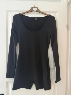 Svart långärmad body  - Stilren svart body från H&M med långa ärmar och djup rundad ringning fram. Tillverkad i ett stretchigt och mjukt material som sitter tajt mot kroppen. 