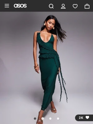 Mörkgrön långklänning/balkänning med volang - Snygg mörkgrön långklänning från ASOS med volangdetaljer och snörning i ryggen. I nyskick med lapp och orginalförpackning kvar. Perfekt som balklänning eller fin klänning på sommaren. Nypris 639kr.