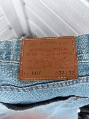 Levi's 501 ljusblå jeans W32 L32 - Klassiska Levi's 501 jeans i ljusblå tvätt med rak passform och knappgylf. Jeansen har fem fickor och är tillverkade i slitstark bomull. Perfekta för en avslappnad och tidlös stil.