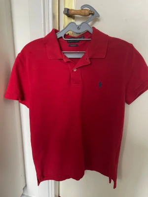 Röd pikétopp från Ralph Lauren - Röd piké från Ralph Lauren. Storlek     Det står medium men passar som S/XS.    Jättebra inget fel bara för liten för mig.     Nypris runt 1000 kr.