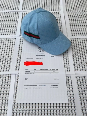 Ljusblå Gci keps med G-mönster - Säljer en ljusblå keps från Gci med det klassiska G-monogrammet över hela kepsen. På sidan finns en grön och röd rand som ger en ikonisk touch. Kepsen har böjd skärm och är tillverkad i ett slitstarkt tyg som känns lyxigt.