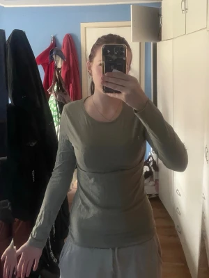 Olivgrön långärmad topp Monki - Säljer en enkel och stilren olivgrön långärmad topp från Monki. Toppen har rund halsringning och är i ett mjukt bomullsmaterial som sitter tight mot kroppen. Perfekt att matcha med jeans eller kjol för en clean look.