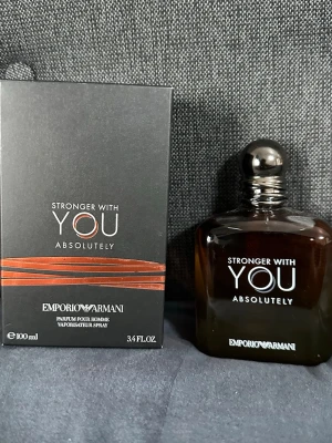 Emporio Armani Stronger With You - Emporio Armani Stronger With You Absolutely är en herrparfym i en elegant, mörkbrun glasflaska med rundade kanter och silverfärgad kork. Flaskan rymmer 100 ml och doften har en modern och maskulin känsla. Förpackningen är svart med kopparfärgade detaljer.