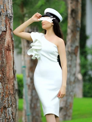 Vit asymmetrisk klänning med volang - Stilren vit klänning med en axel och volangdetalj framtill. Figurnära passform och knälång längd. Perfekt för dig som vill sticka ut med en elegant och modern look. Materialet ser ut att vara mjukt och stretchigt för en bekväm känsla.